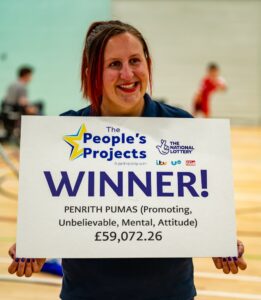 Megan Pettit from Penrith Pumas wheelchair rugby club holds a large card reading the peoples project winners. The club were awarded £59,072.26