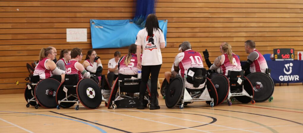 A wheelchair rugby team huddle together to discuss game tactics