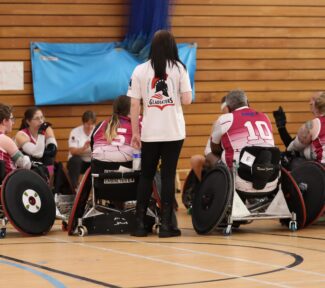 A wheelchair rugby team huddle together to discuss game tactics
