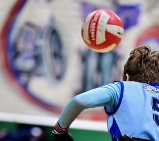 Female wheelchair rugby player chasing the ball