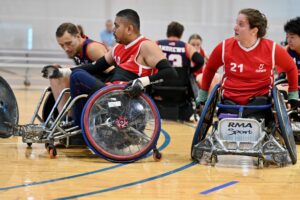 two male and one female wheelchair rugby player in a court